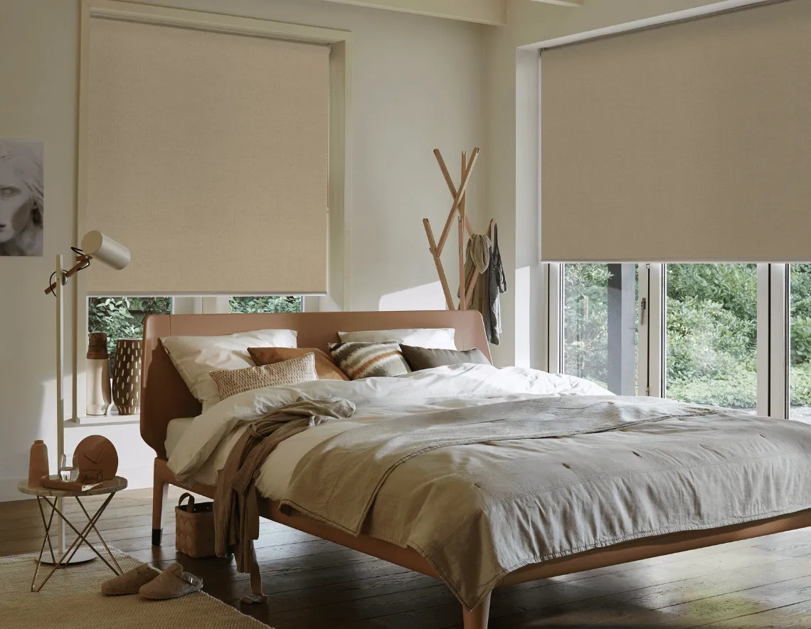 Cortinas Roller en tela Black Out color beige, para habitación. Muebles de madera y grandes ventanales.