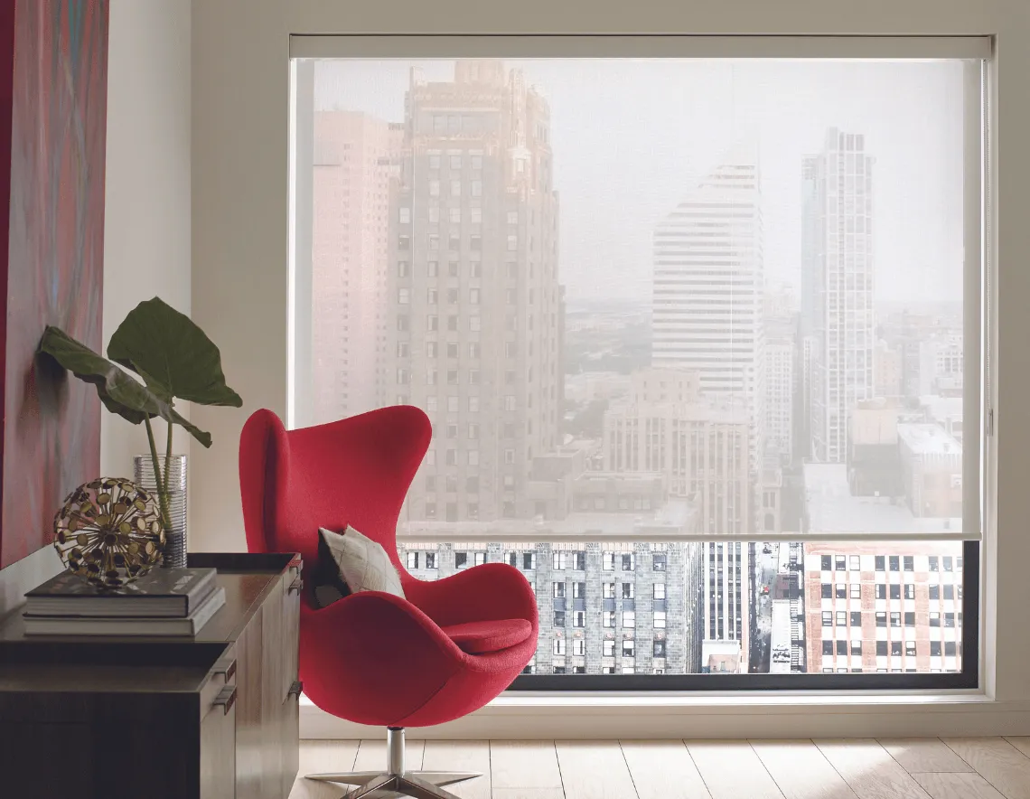 Cortina Roller en tela screen, color blanco. Filtran luz natural en moderna sala de estar con sillon rojo y deco.